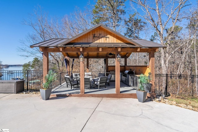 exterior space featuring an outdoor kitchen, a water view, an outdoor hangout area, a gazebo, and ceiling fan