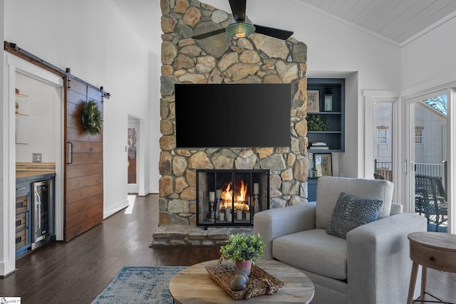 living room featuring wine cooler, ceiling fan, a barn door, a fireplace, and dark hardwood / wood-style flooring