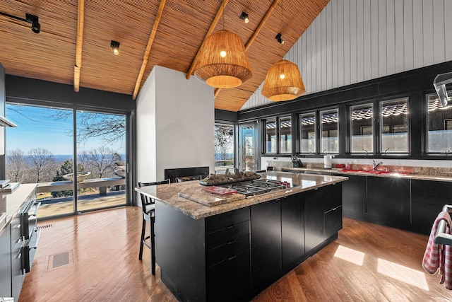 kitchen with wood ceiling, stainless steel gas stovetop, a center island, and hanging light fixtures