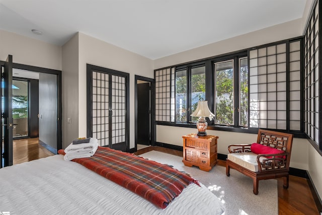 bedroom with access to exterior, hardwood / wood-style flooring, and french doors