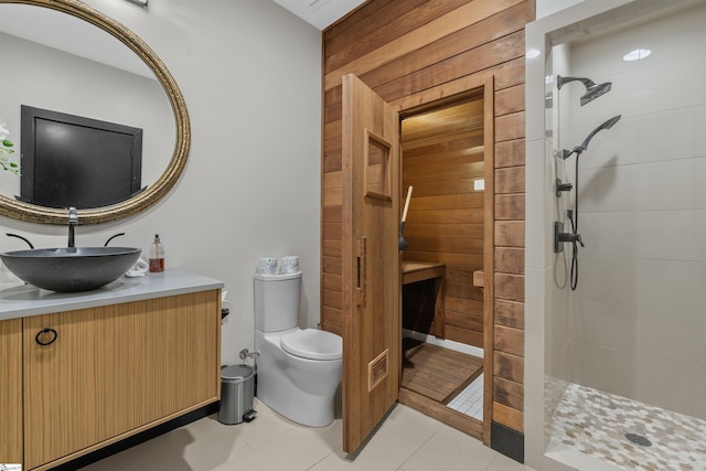 bathroom featuring a tile shower, vanity, toilet, and wood walls