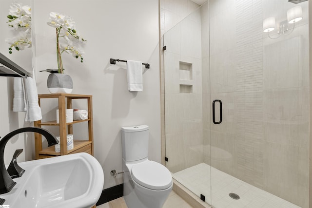 bathroom featuring sink, a shower with door, and toilet