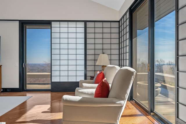 living area with a wall of windows, lofted ceiling, and light hardwood / wood-style flooring