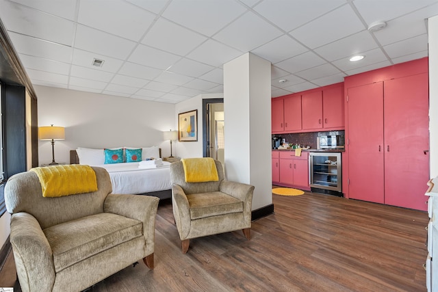 bedroom with dark wood-type flooring, bar area, beverage cooler, and a drop ceiling