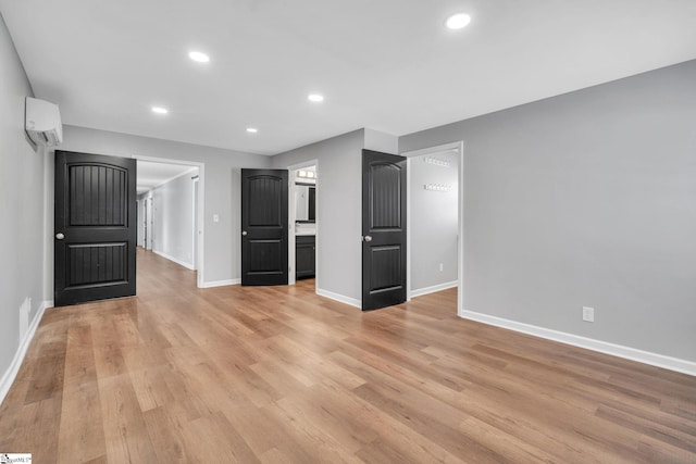 unfurnished living room featuring a wall mounted AC and light hardwood / wood-style floors