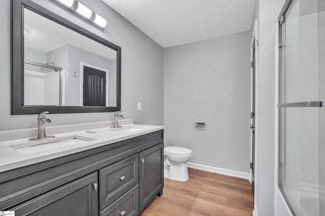 bathroom with hardwood / wood-style floors, vanity, toilet, and a shower with shower door