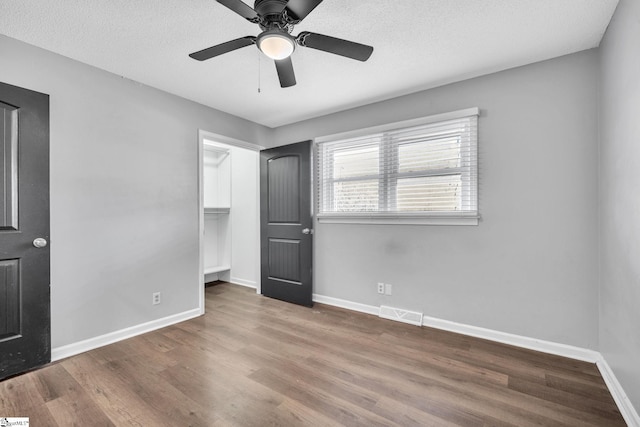 unfurnished bedroom featuring ceiling fan, a closet, a spacious closet, and a textured ceiling