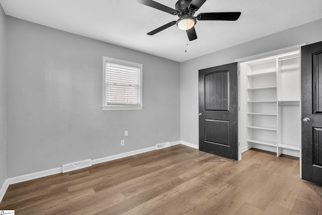 unfurnished bedroom featuring ceiling fan, a closet, a textured ceiling, and light hardwood / wood-style flooring