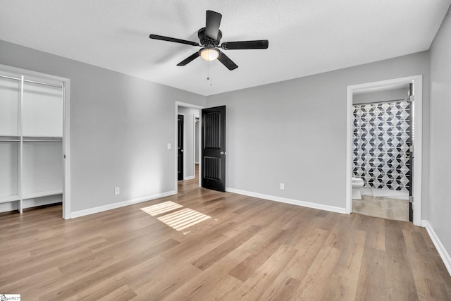 unfurnished bedroom featuring ensuite bathroom, ceiling fan, light wood-type flooring, a textured ceiling, and a closet