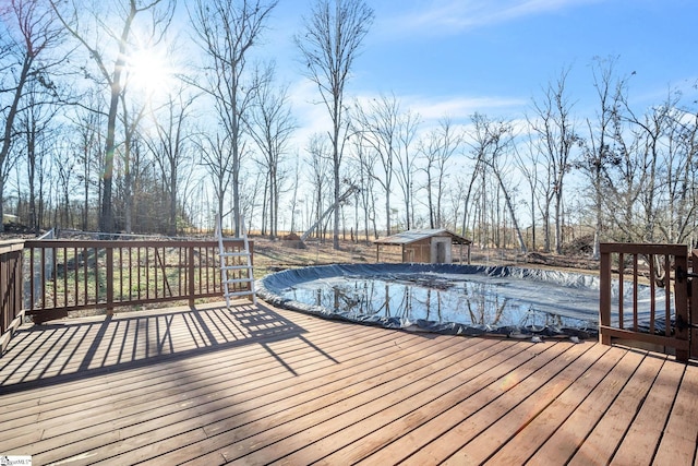 wooden terrace with a covered pool and a storage shed