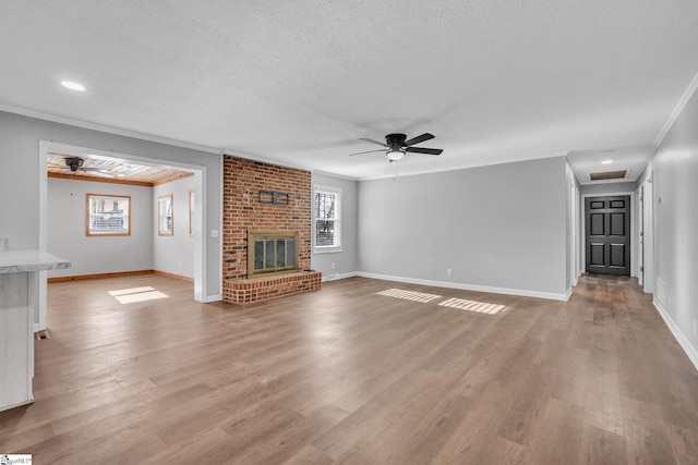 unfurnished living room with crown molding, a fireplace, ceiling fan, and light wood-type flooring