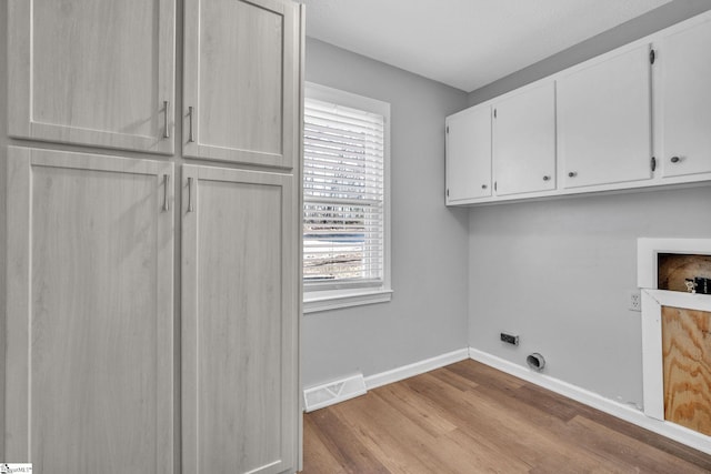 laundry area with electric dryer hookup, hookup for a washing machine, cabinets, and light wood-type flooring