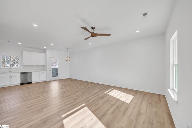 unfurnished living room with sink, light hardwood / wood-style floors, plenty of natural light, and ceiling fan