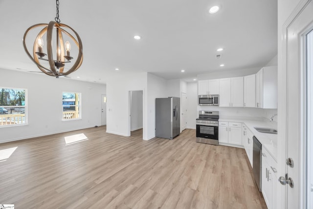 kitchen featuring pendant lighting, sink, appliances with stainless steel finishes, white cabinetry, and a chandelier