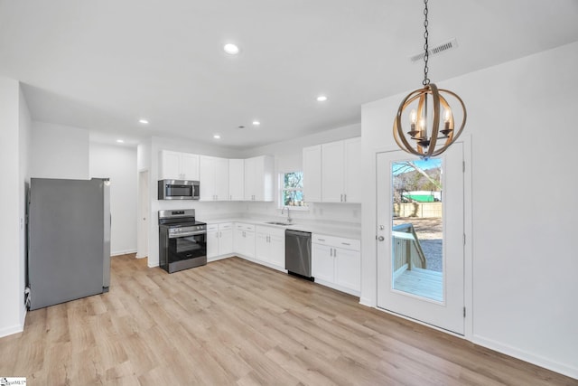 kitchen featuring appliances with stainless steel finishes, sink, decorative light fixtures, a notable chandelier, and white cabinets