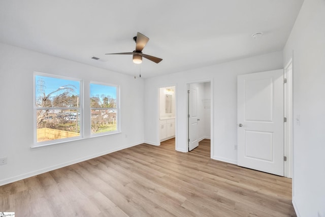 unfurnished bedroom with ceiling fan, a spacious closet, light hardwood / wood-style flooring, connected bathroom, and a closet