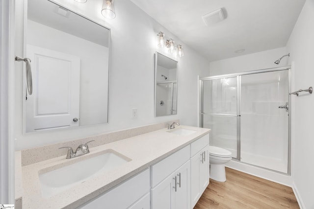 bathroom with hardwood / wood-style floors, vanity, toilet, and a shower with door