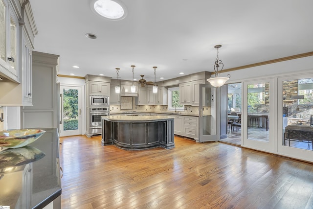 kitchen featuring appliances with stainless steel finishes, gray cabinetry, a healthy amount of sunlight, decorative light fixtures, and a kitchen island