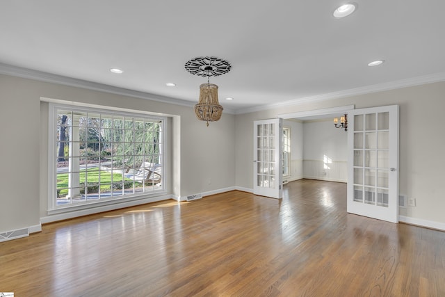 empty room with french doors, crown molding, and a notable chandelier