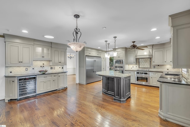 kitchen featuring pendant lighting, a center island, wine cooler, built in appliances, and gray cabinets