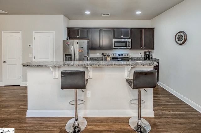 kitchen with a breakfast bar area, an island with sink, and appliances with stainless steel finishes