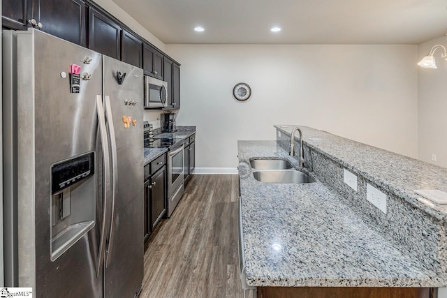 kitchen with sink, light stone countertops, stainless steel appliances, and dark wood-type flooring