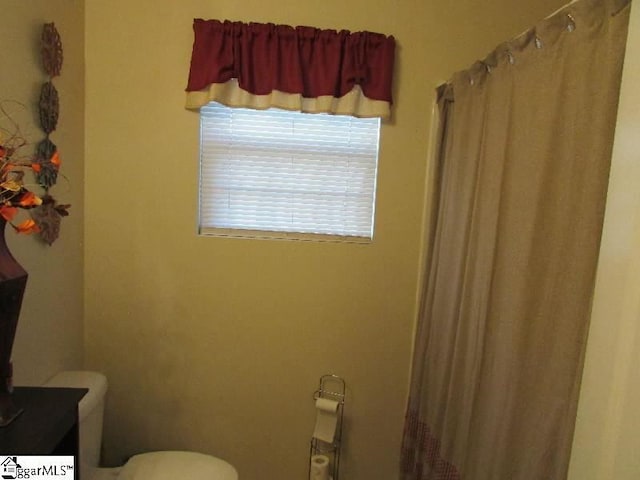 bathroom with a shower with curtain and toilet