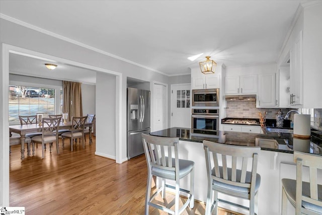 kitchen featuring kitchen peninsula, white cabinetry, decorative backsplash, and appliances with stainless steel finishes