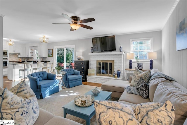 living room featuring ceiling fan, a fireplace, and ornamental molding