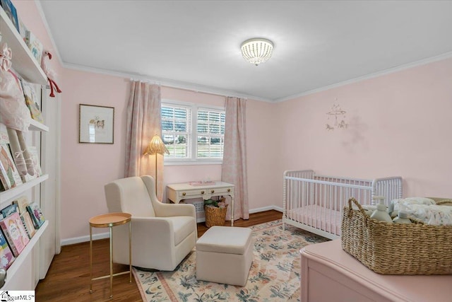 bedroom with hardwood / wood-style flooring, a nursery area, and ornamental molding