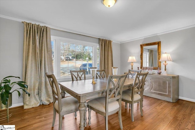 dining room with light wood-type flooring and crown molding