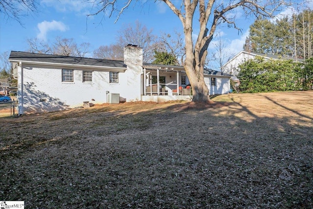 rear view of property with a sunroom, central air condition unit, and a yard