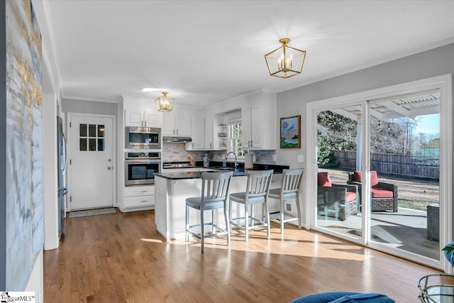 kitchen featuring backsplash, kitchen peninsula, a notable chandelier, white cabinetry, and stainless steel appliances