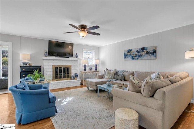 living room with ceiling fan, wood-type flooring, and a fireplace