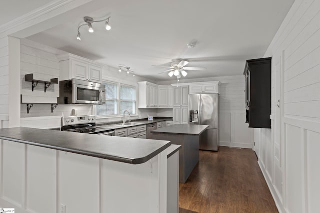 kitchen featuring white cabinets, stainless steel appliances, kitchen peninsula, and dark wood-type flooring