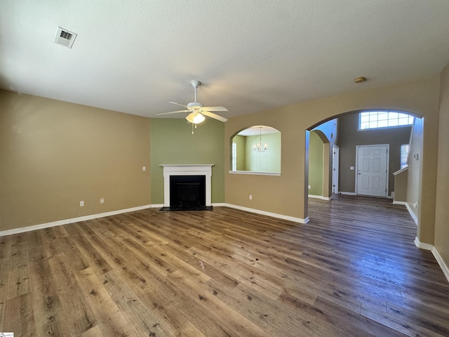 unfurnished living room featuring wood-type flooring and ceiling fan with notable chandelier