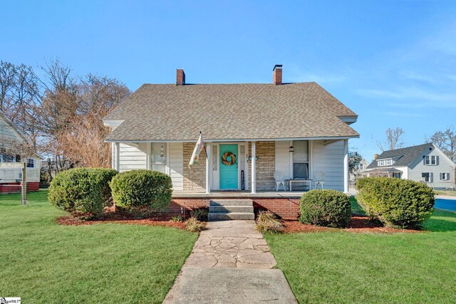 bungalow-style house featuring covered porch and a front lawn