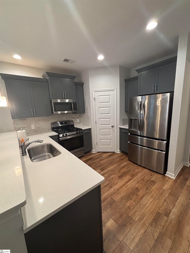 kitchen with stainless steel appliances, gray cabinets, dark hardwood / wood-style floors, and sink