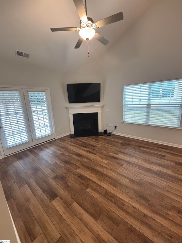 unfurnished living room with lofted ceiling, ceiling fan, dark hardwood / wood-style flooring, and plenty of natural light