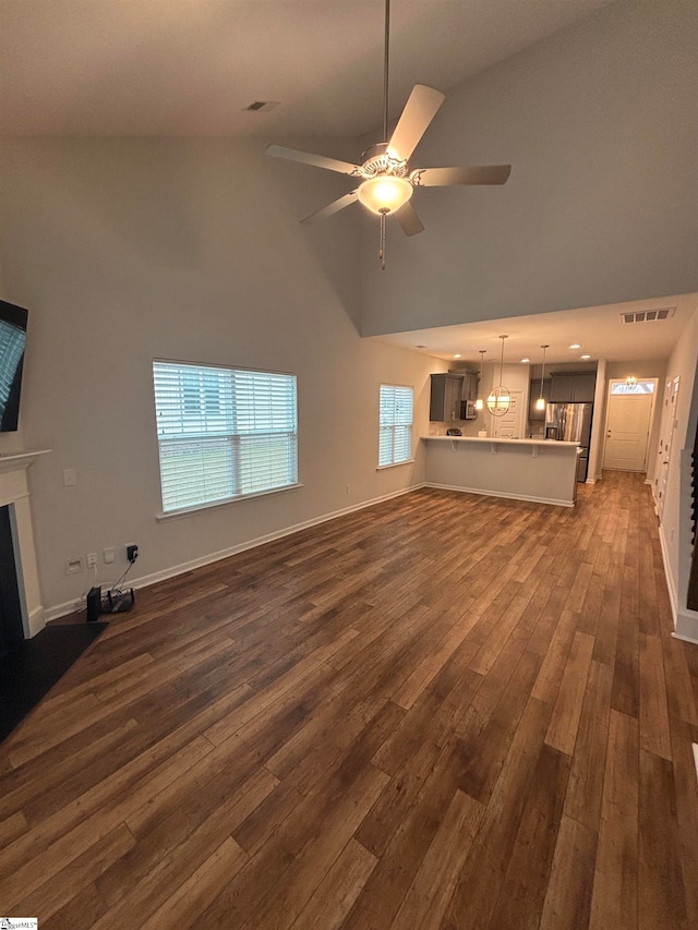 unfurnished living room featuring dark hardwood / wood-style floors, high vaulted ceiling, and ceiling fan