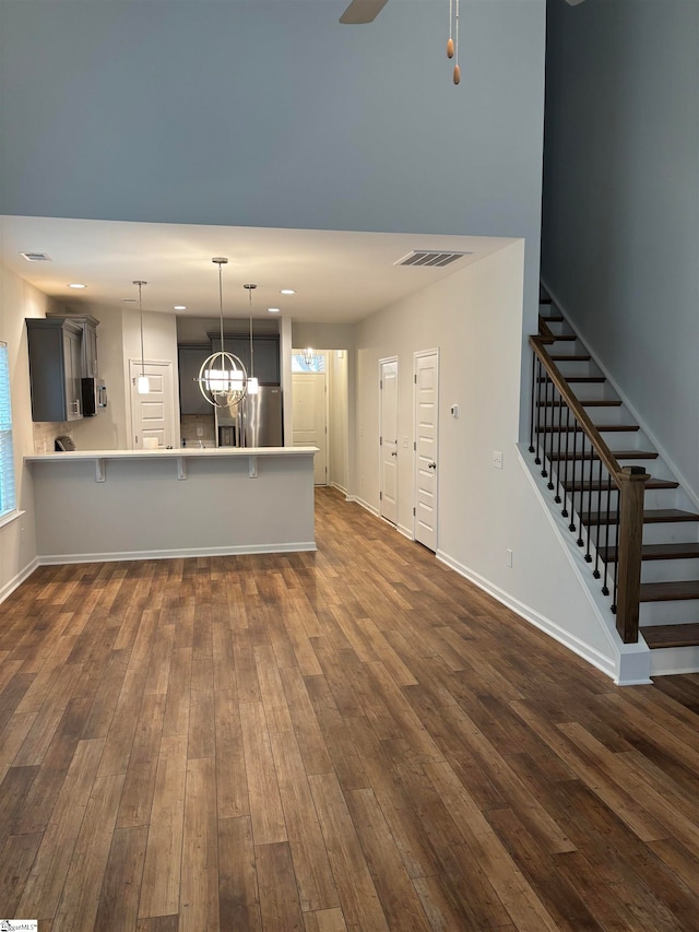 kitchen featuring gray cabinetry, stainless steel fridge with ice dispenser, dark hardwood / wood-style flooring, kitchen peninsula, and a breakfast bar