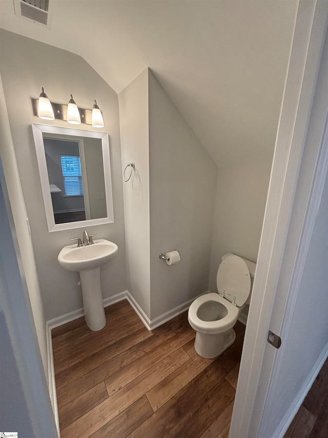 bathroom featuring wood-type flooring, toilet, and lofted ceiling