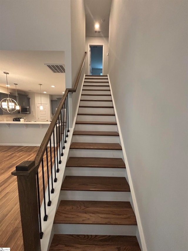 stairs with an inviting chandelier