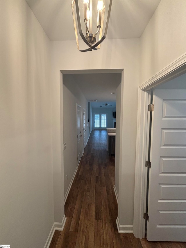 hallway featuring dark hardwood / wood-style flooring and a notable chandelier