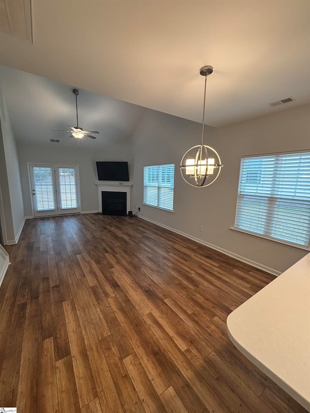 unfurnished living room with ceiling fan with notable chandelier, dark hardwood / wood-style floors, and lofted ceiling