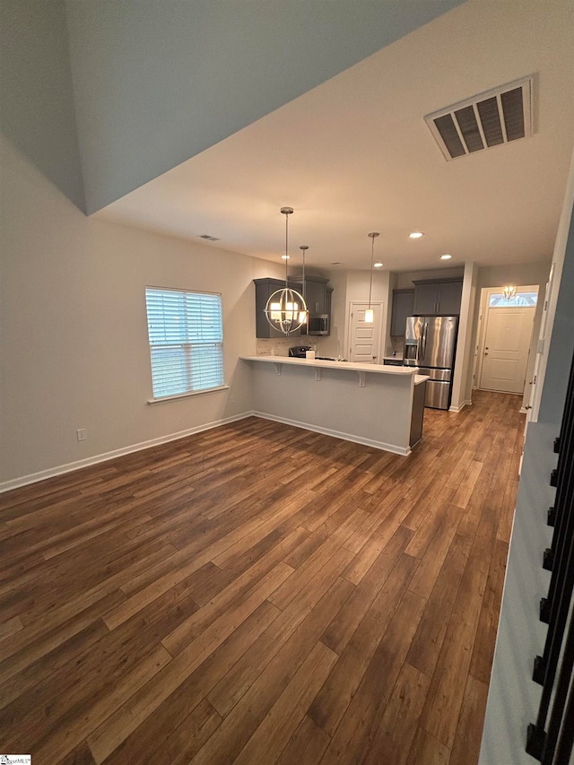 unfurnished living room featuring a chandelier and dark wood-type flooring