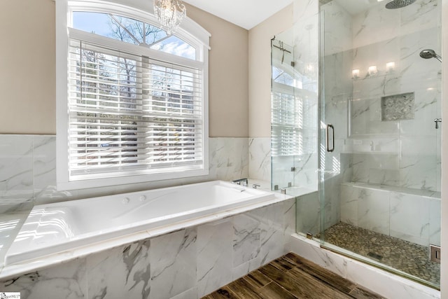 bathroom with hardwood / wood-style flooring, independent shower and bath, and an inviting chandelier