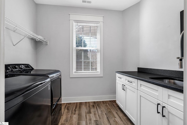 laundry area with cabinets, separate washer and dryer, dark hardwood / wood-style floors, and sink