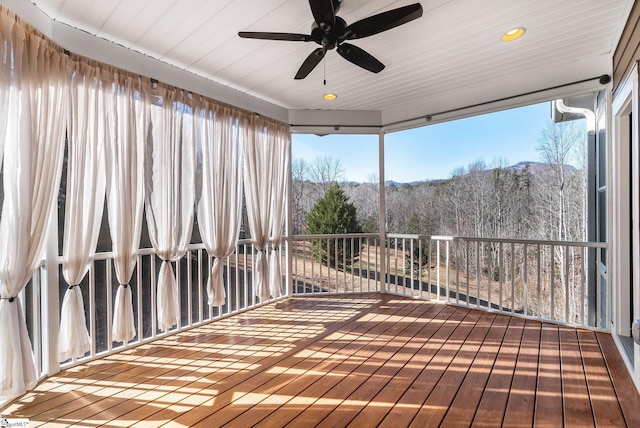 unfurnished sunroom featuring a wealth of natural light, ceiling fan, and a mountain view