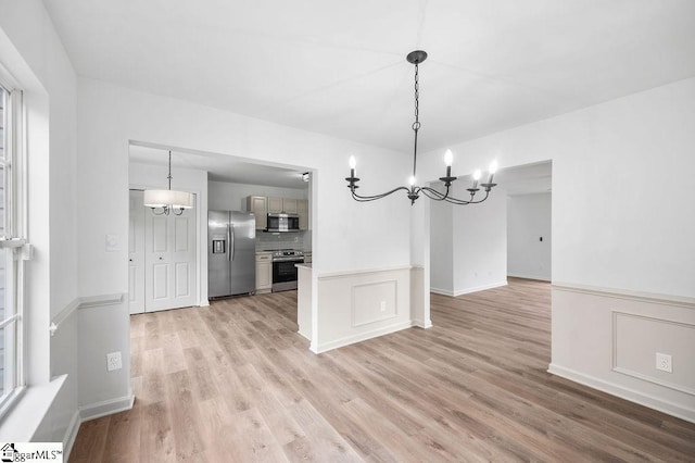 unfurnished dining area featuring a chandelier and light hardwood / wood-style flooring